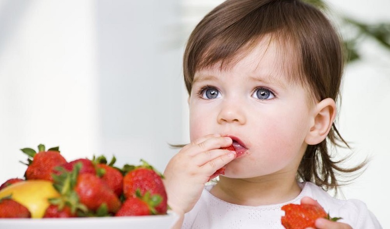 девочка кушает клубнику
