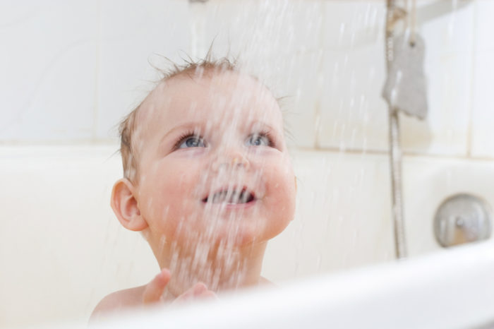 Ребенок закаляется в ванной и улыбается